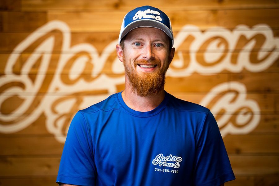 A man with a beard is wearing a blue shirt and hat.