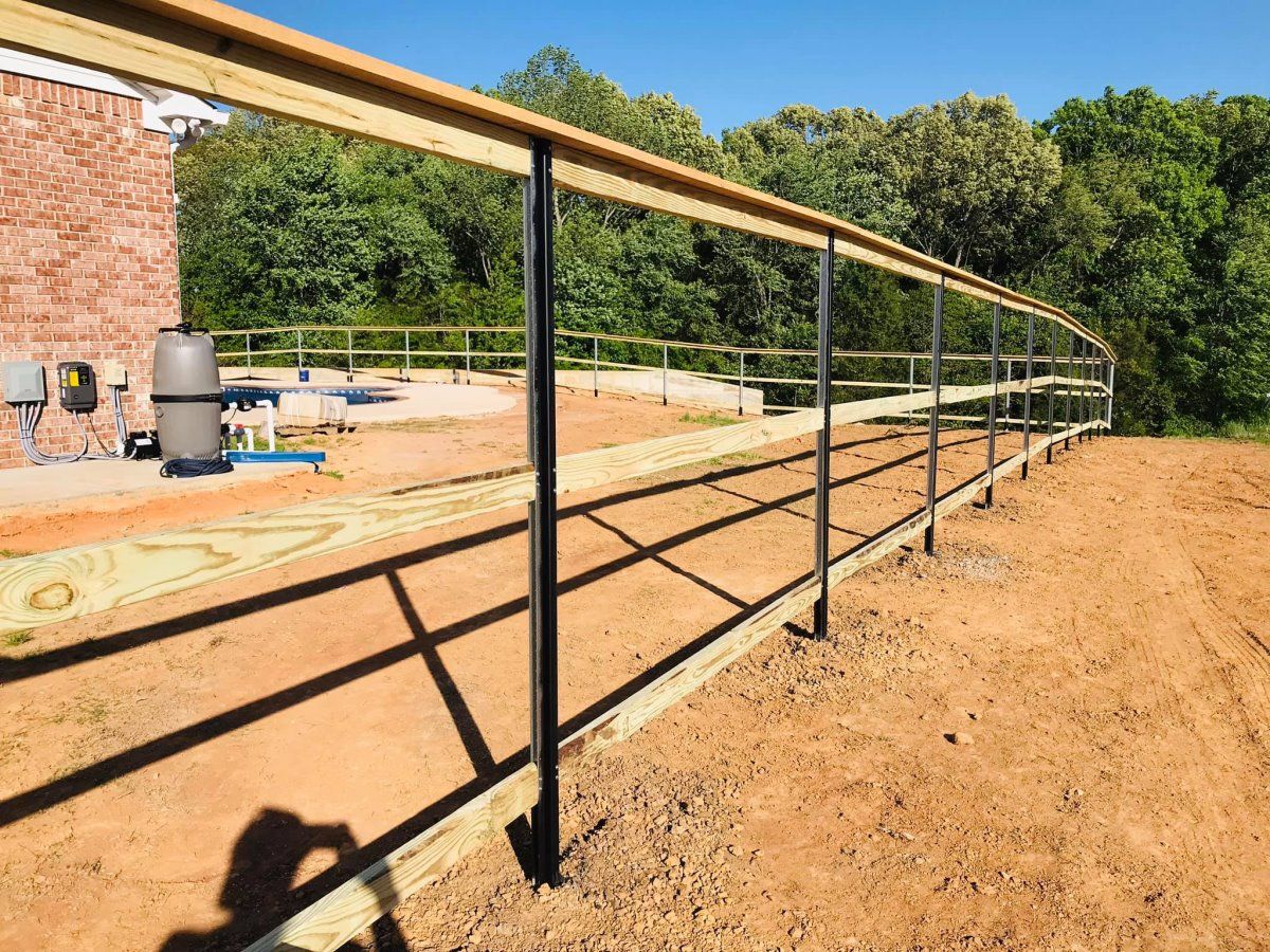 A wooden fence is being built in a dirt field.