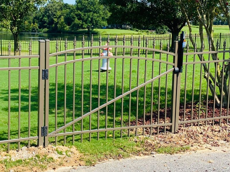 A wrought iron fence surrounds a lush green field.