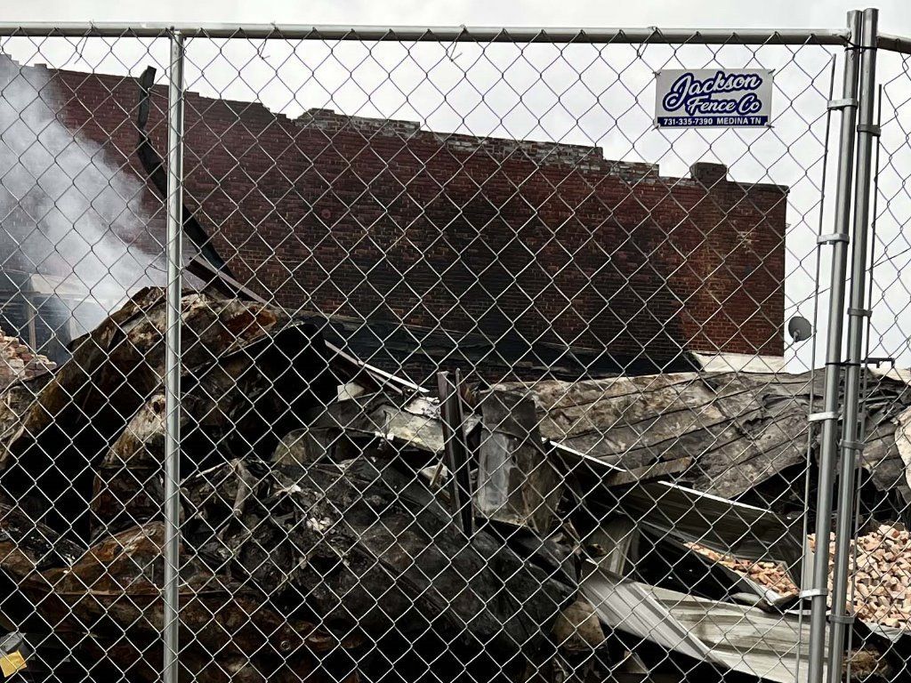 A chain link fence surrounds a pile of rubble.