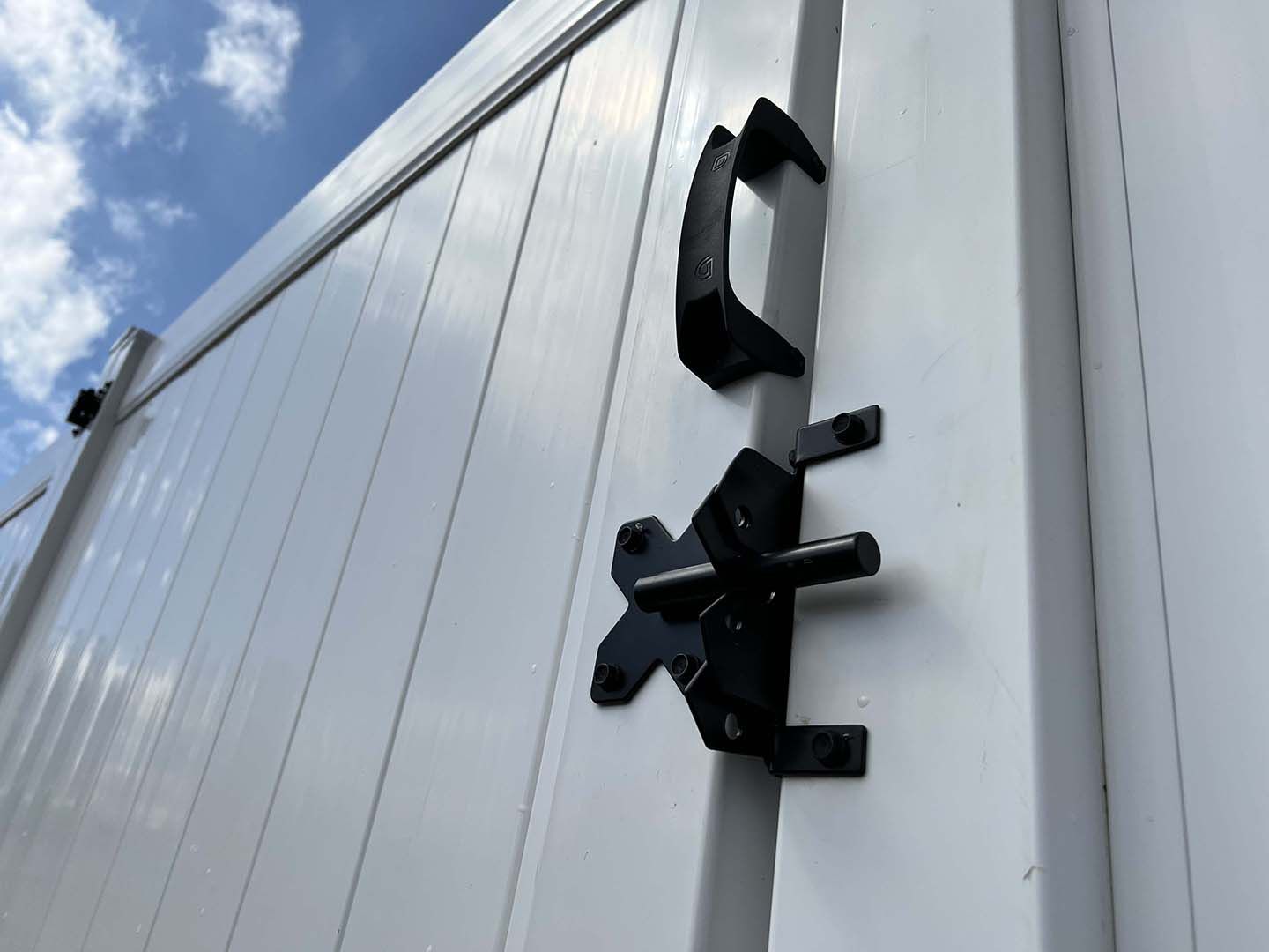 A white fence with a black latch on it.
