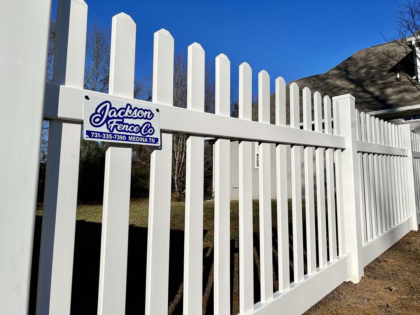 A white picket fence with a sign that says jackson fence co.