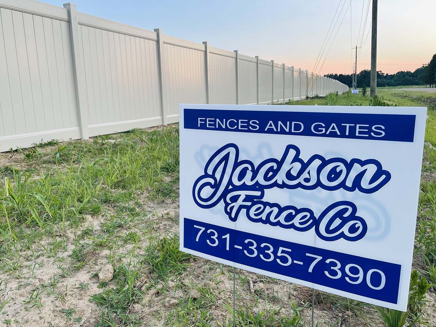 A sign for jackson fence co. is in front of a white fence