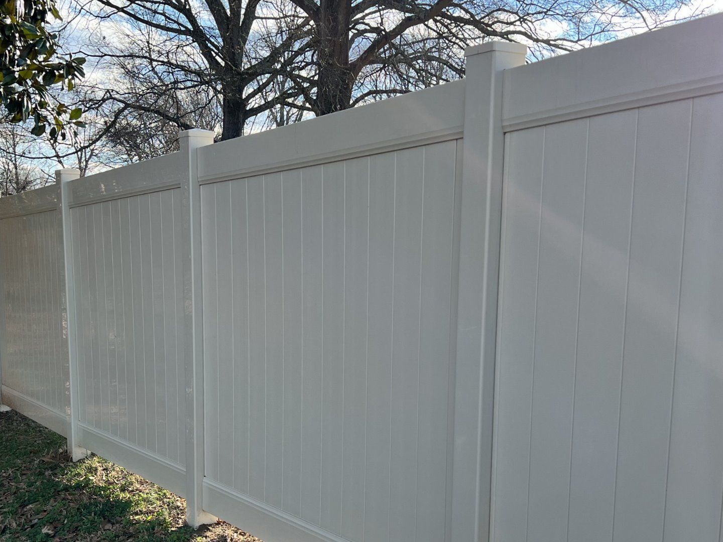 A white vinyl fence with a tree in the background.