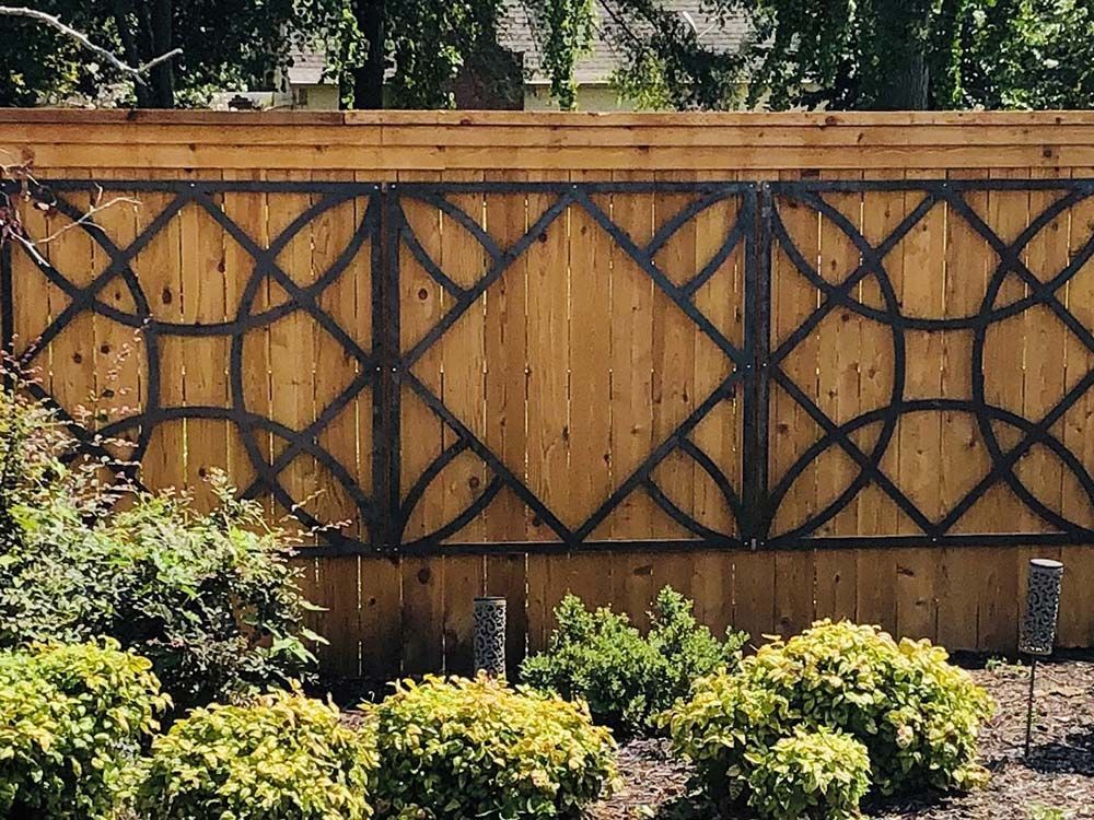 A wooden fence with a metal trellis on it in a garden.