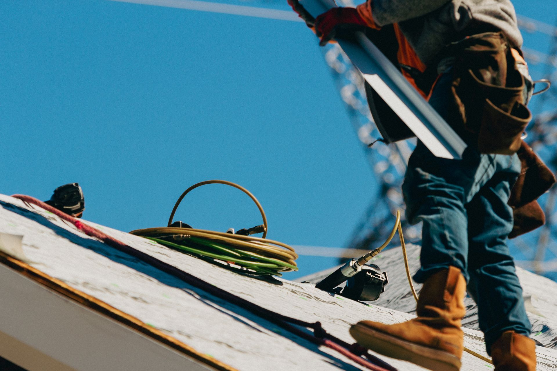 Roofer on a roof holding metal flashing. A blue sky is in the background.