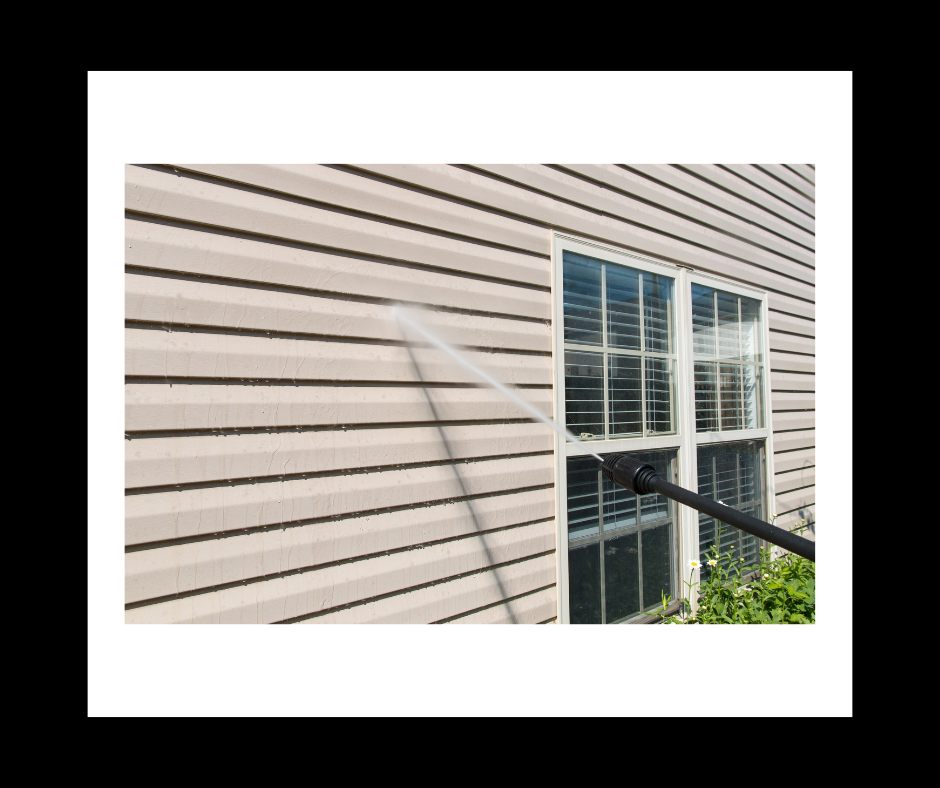 Pressure washing siding of a house with window visible. Water spraying.
