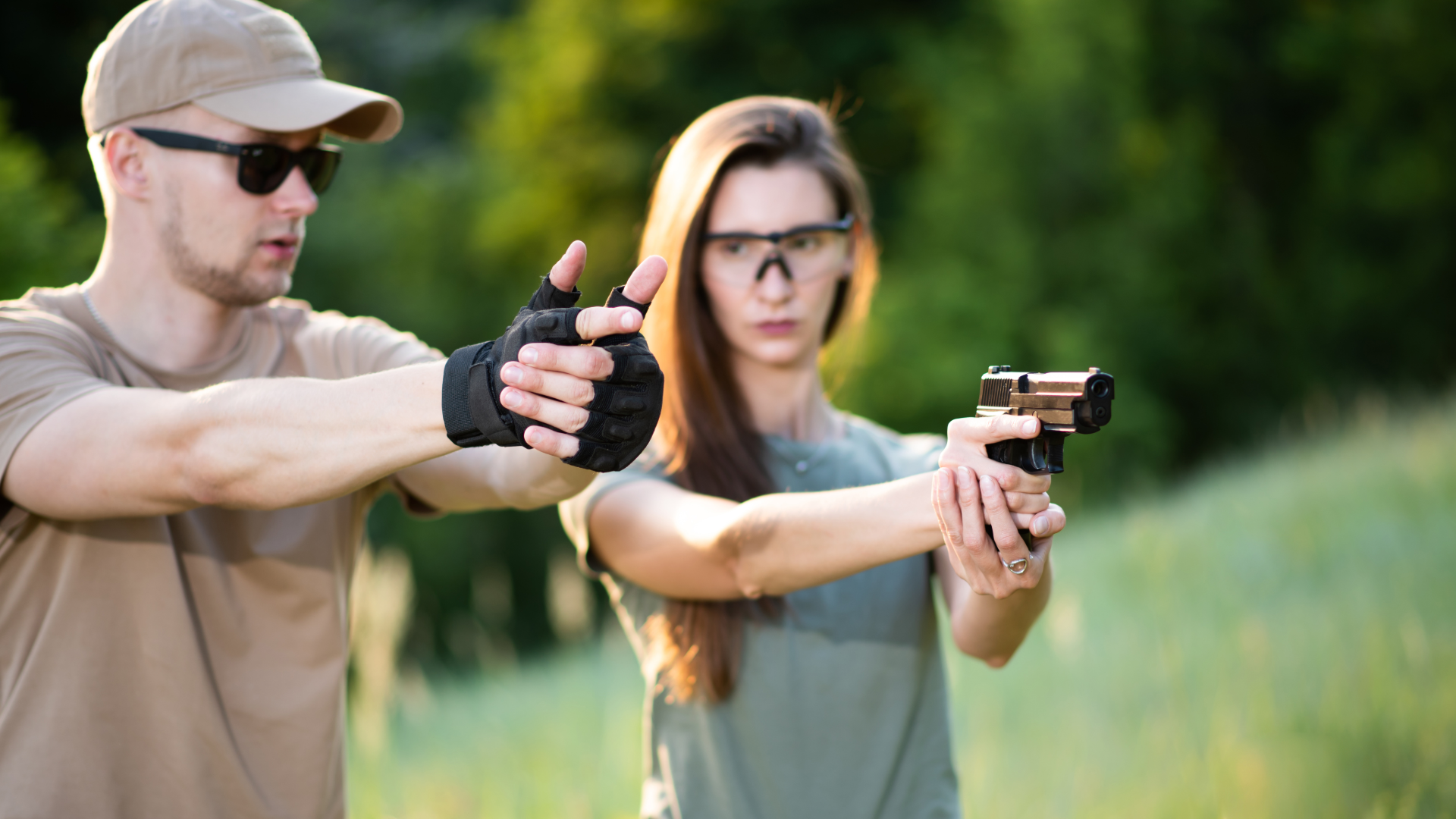 Two people at a shooting range aiming handguns, one wearing ear protection and glasses.