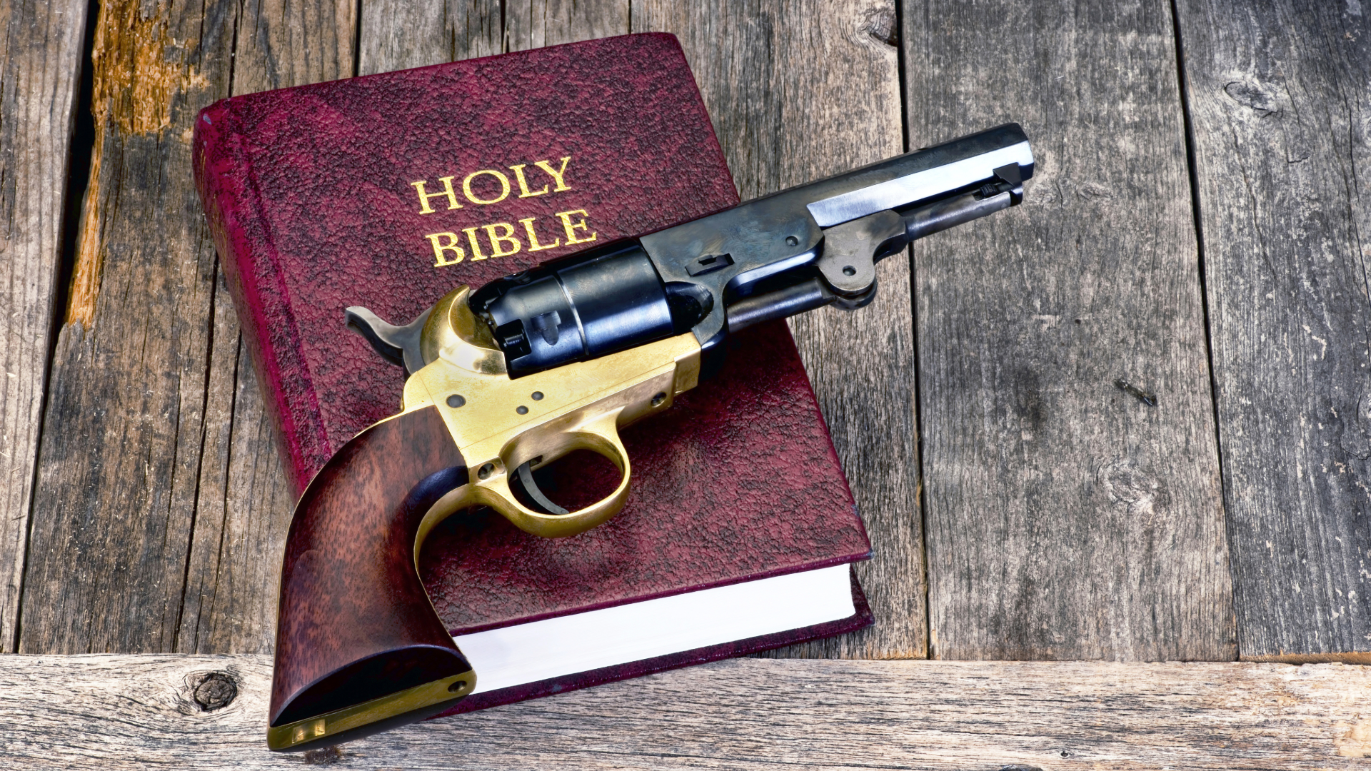 Revolver resting on a Holy Bible on weathered wooden planks