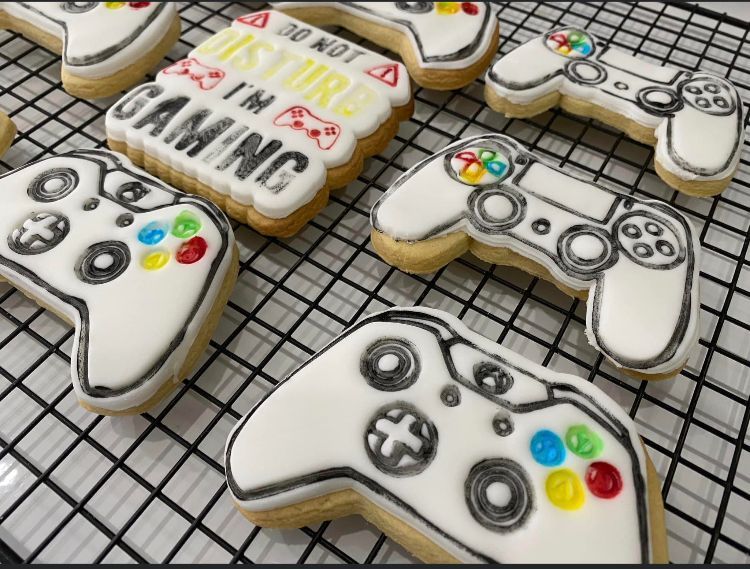 A bunch of video game controller shaped cookies on a cooling rack