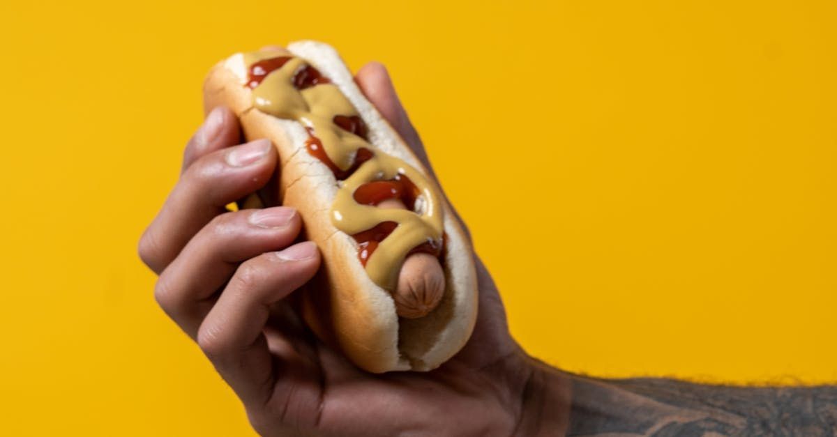 A person is holding a hot dog with mustard and ketchup.