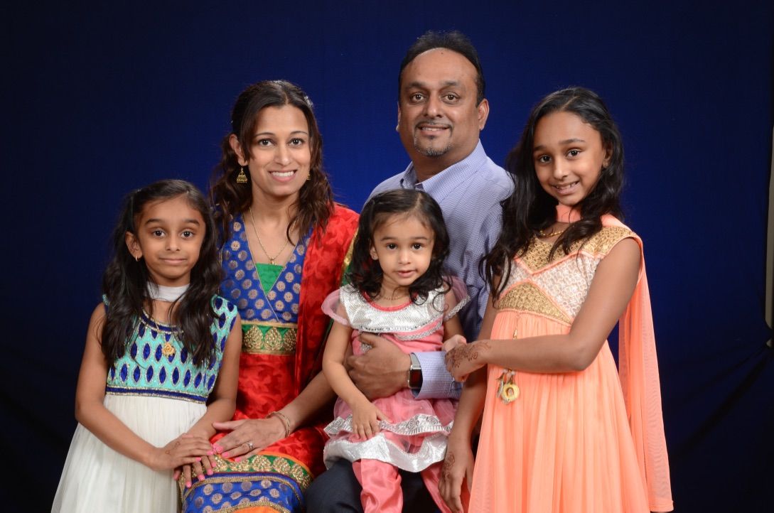 A family is posing for a picture in front of a blue background.