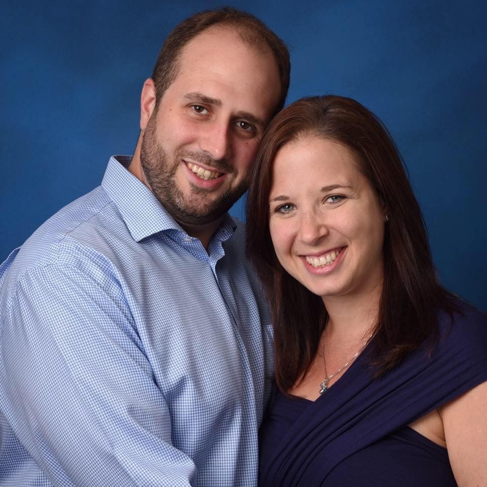 A man and a woman are posing for a picture and smiling for the camera