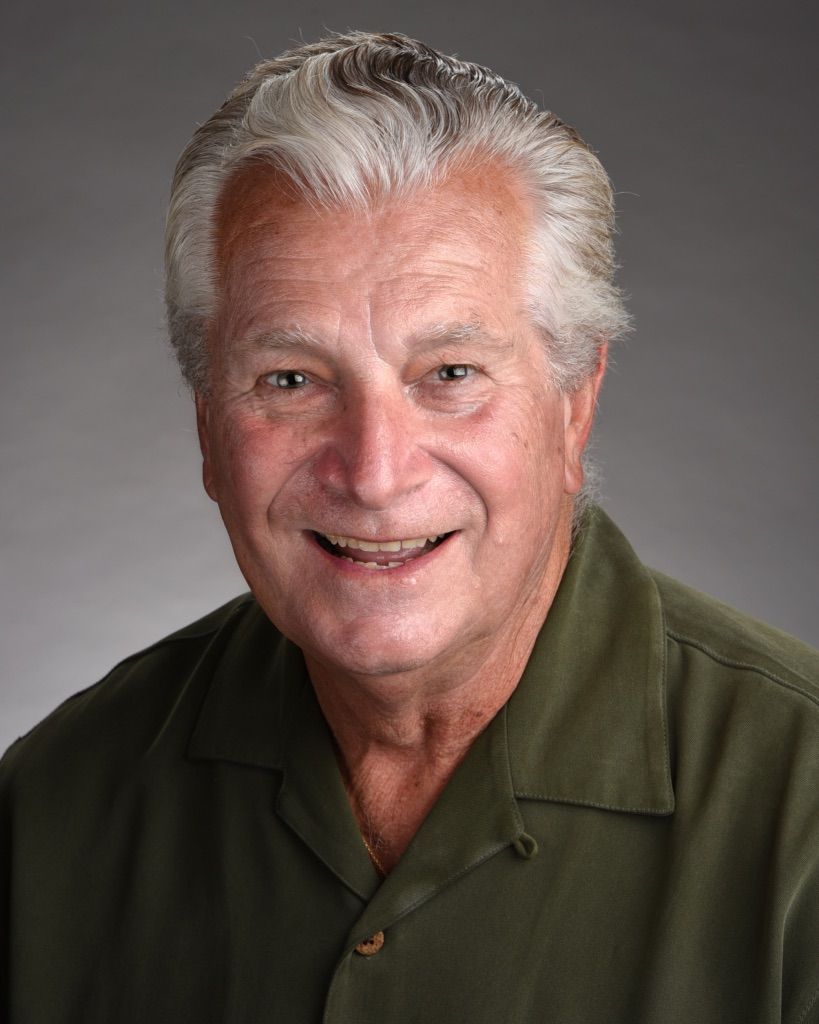 A man in a green shirt is smiling for the camera.