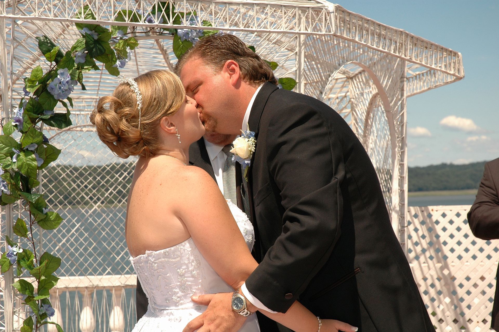 A bride and groom kissing in front of a white gazebo