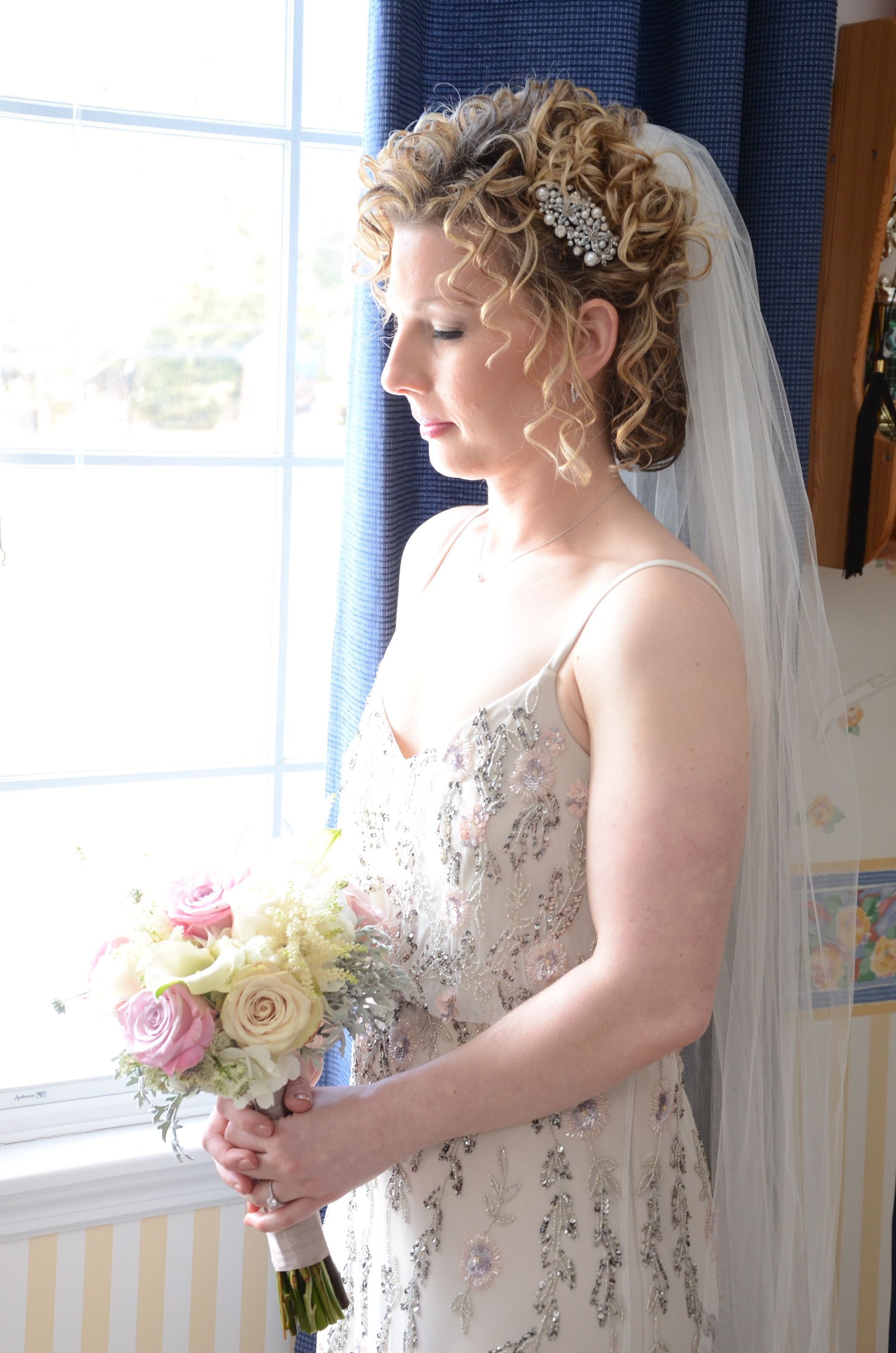 A woman in a wedding dress and veil is holding a bouquet of flowers.