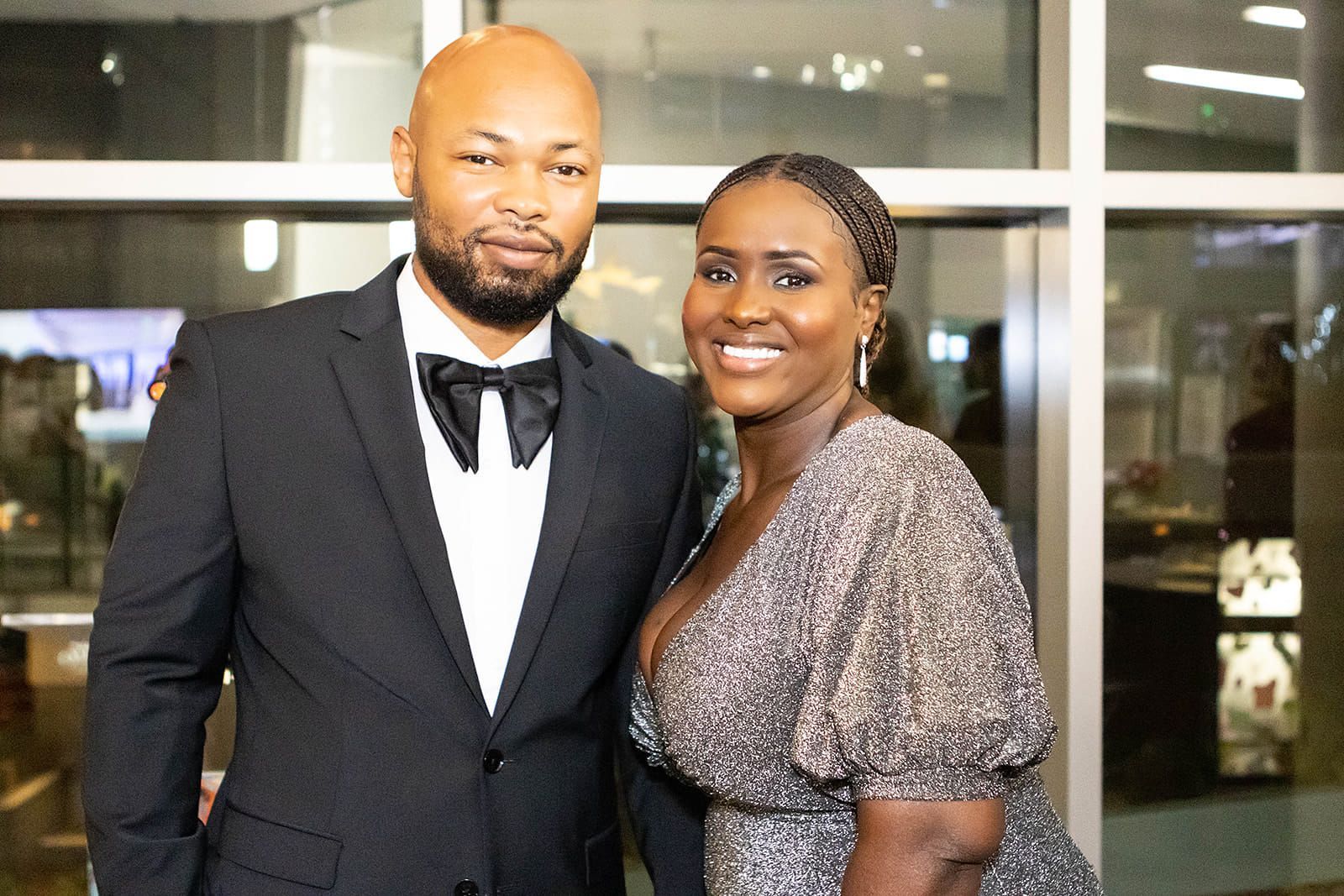 A man and a woman are posing for a picture in front of a window.
