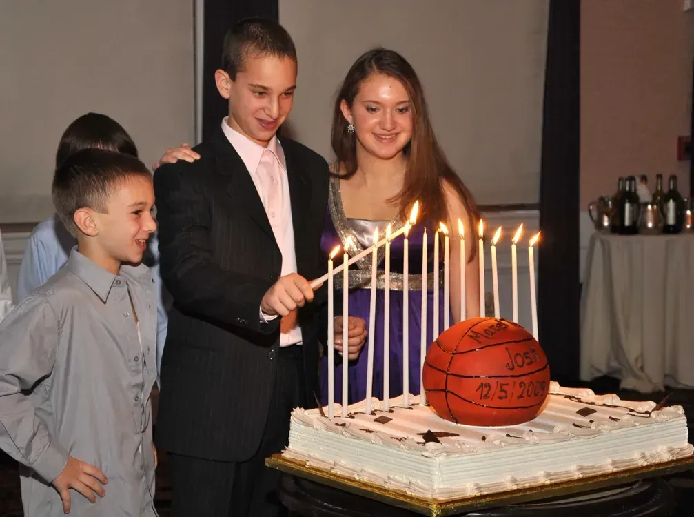 A group of people are lighting candles on a cake with a basketball on it.