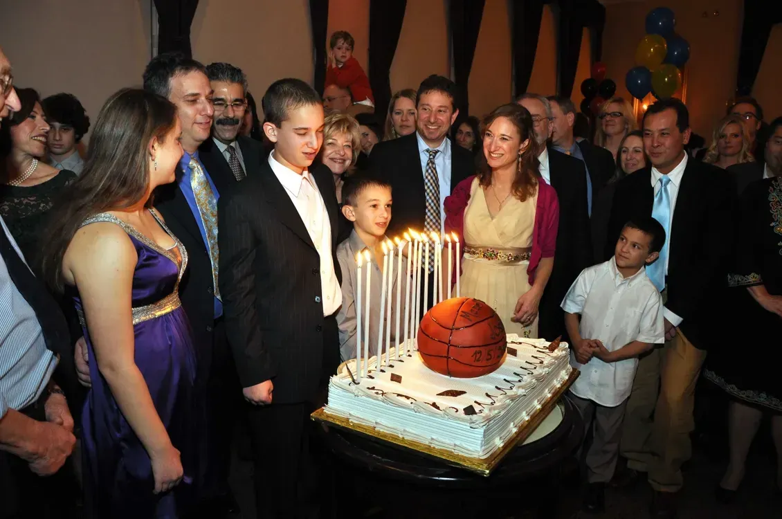 A group of people standing around a cake with a basketball on it