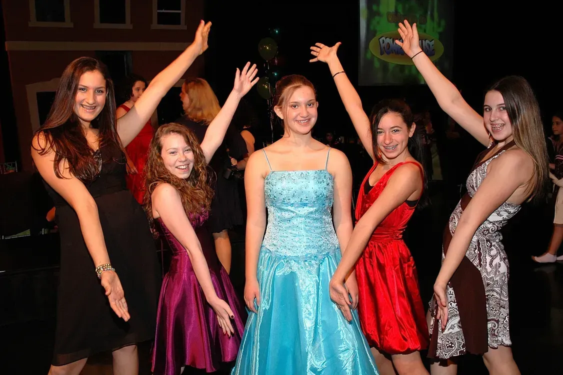 A group of girls are posing for a picture with their arms in the air