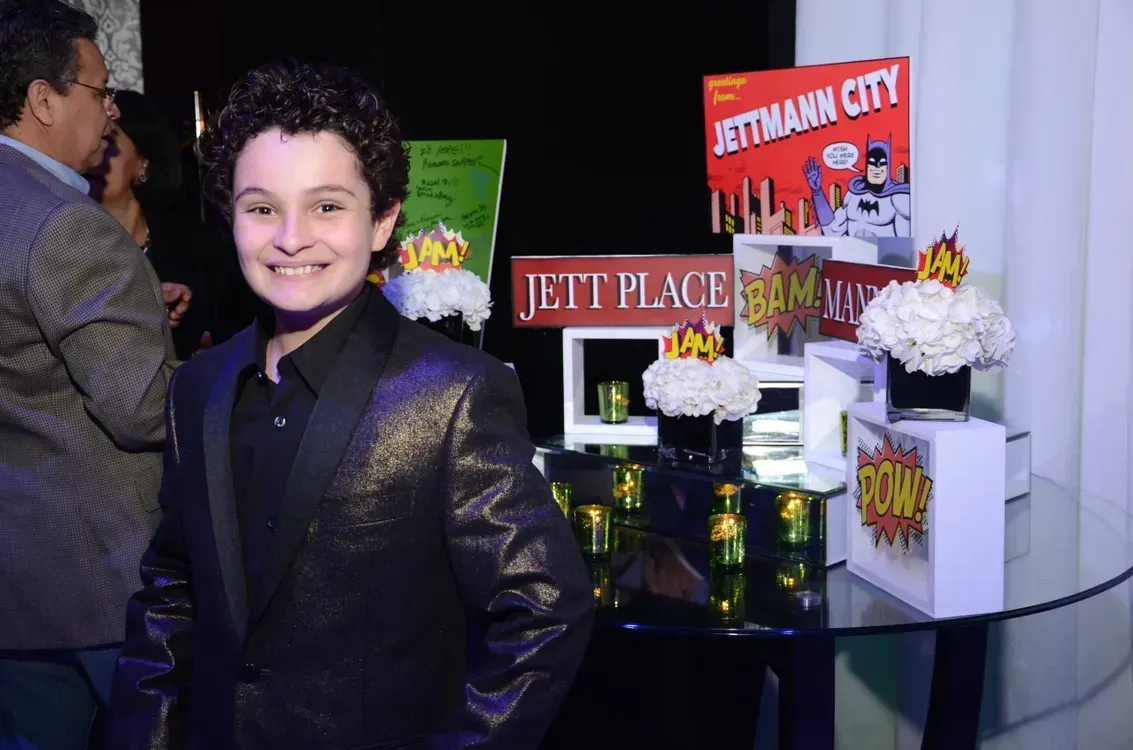 A boy in a suit stands in front of a sign that says jetman city