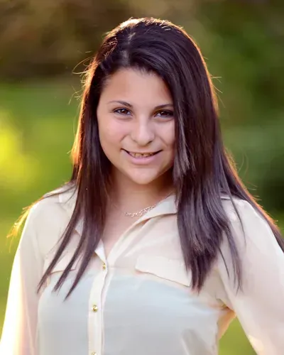 The woman is wearing a white shirt and smiling for the camera.