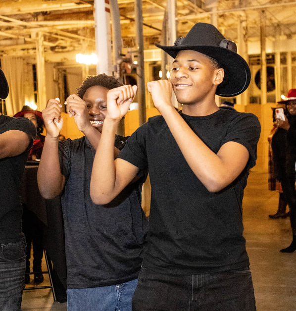 A man wearing a cowboy hat is standing next to another man