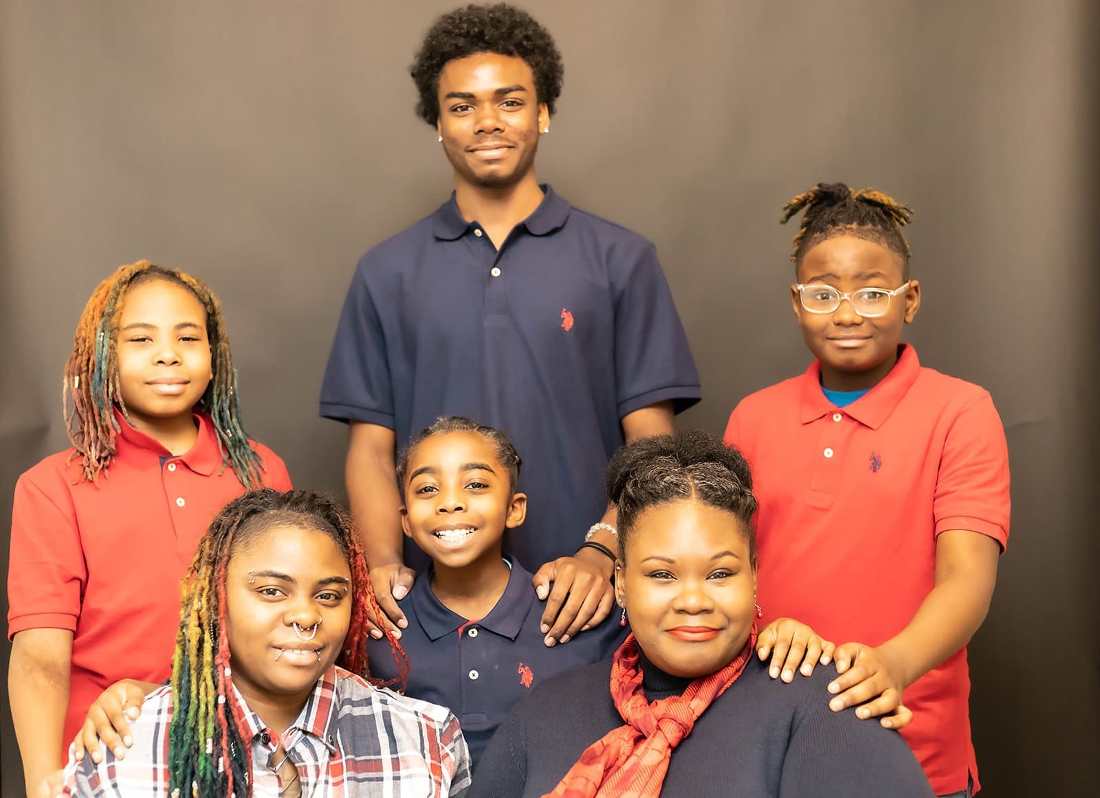 A group of young people posing for a picture in front of a black background.