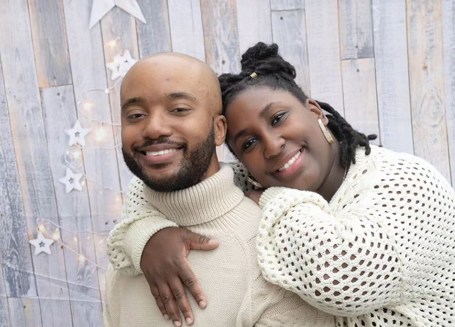 A man and a woman are posing for a picture in front of a wooden wall.