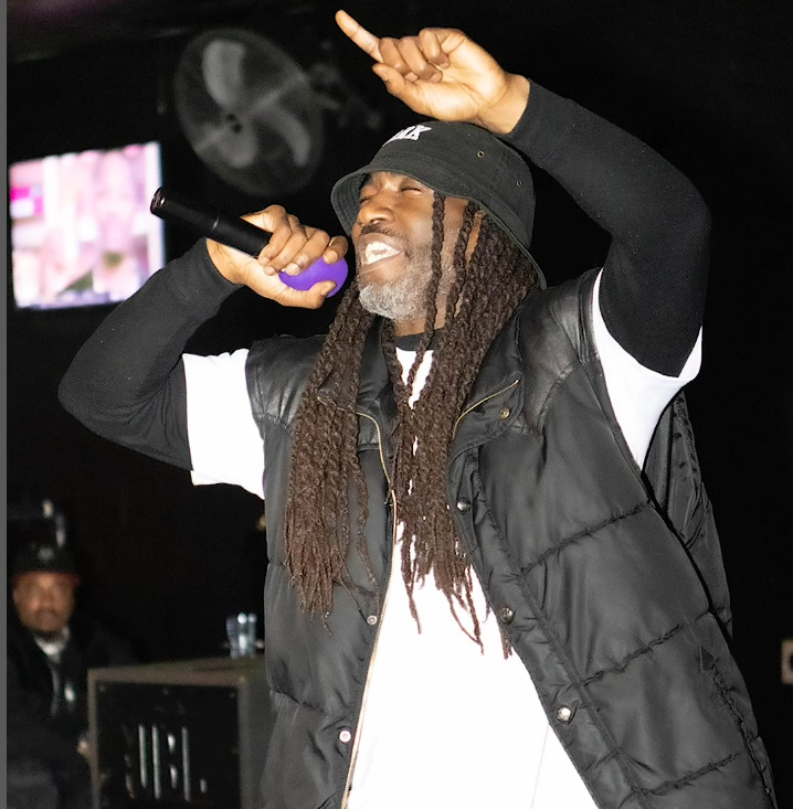 A man with dreadlocks is singing into a microphone