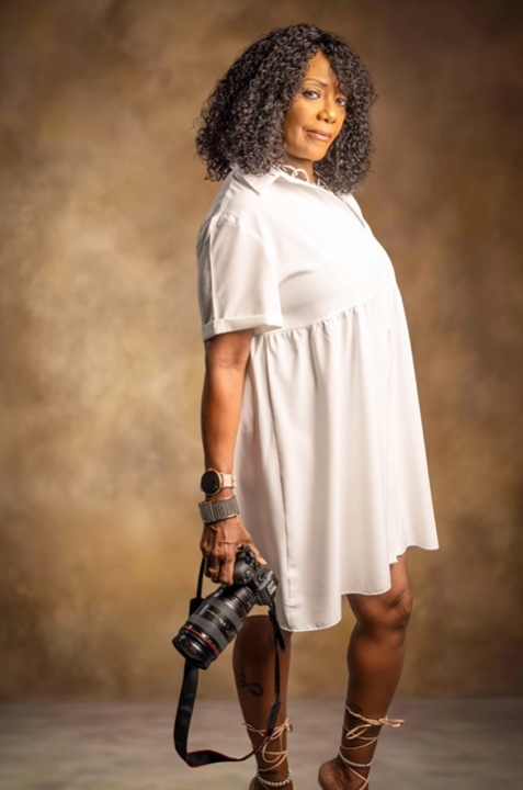 A woman in a white dress is holding a camera.