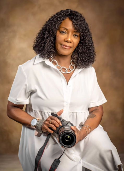 A woman in a white dress is holding a camera.
