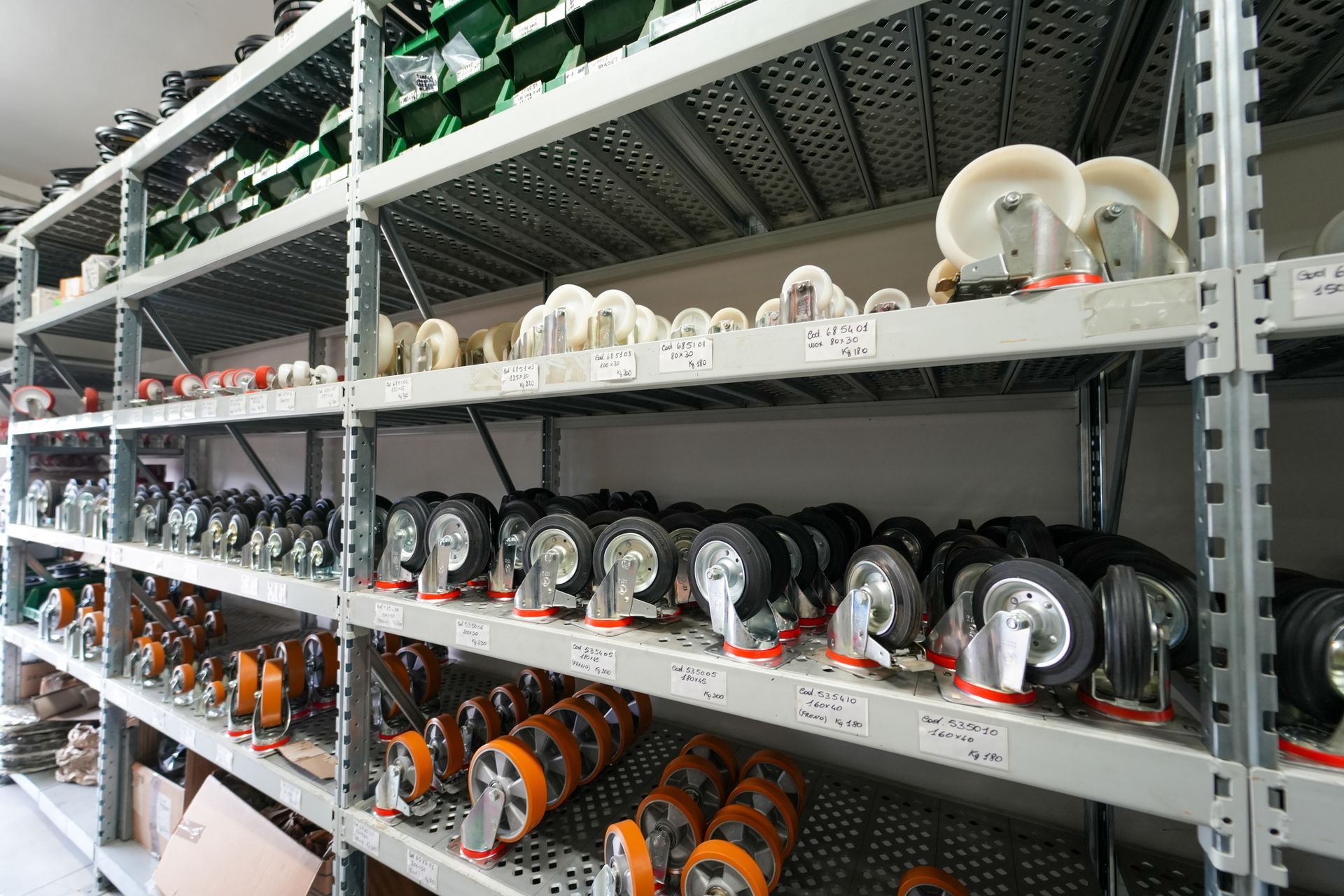Scaffalatura metallica rifornita con vari tipi di ruote e rotelle industriali in un magazzino o in un negozio di forniture.