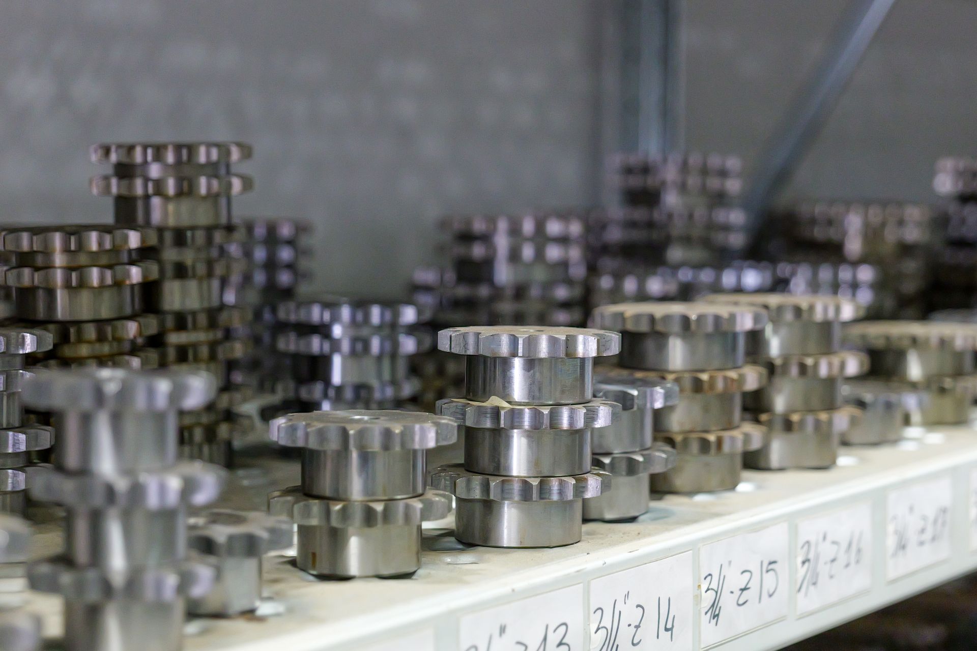 Scaffali in un'officina pieni di file ordinate di ingranaggi metallici industriali.
