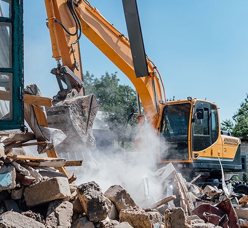 an excavator is demolishing a building with a lot of rocks .