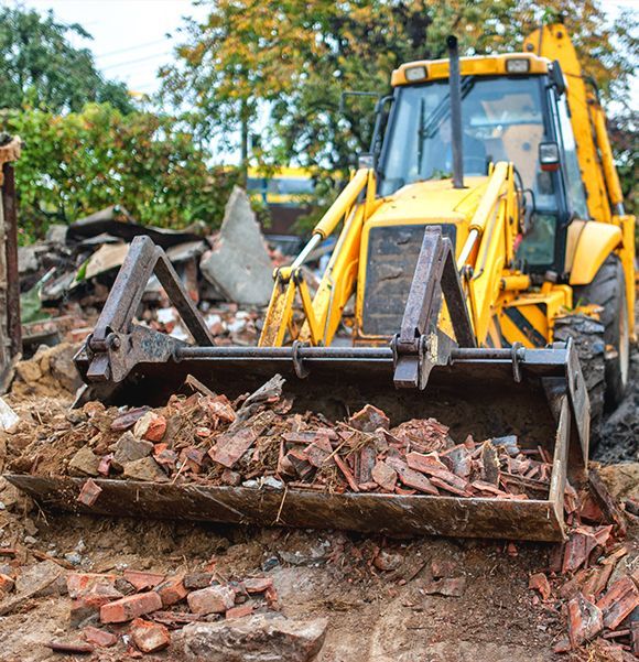 a yellow bulldozer is working on a pile of bricks .