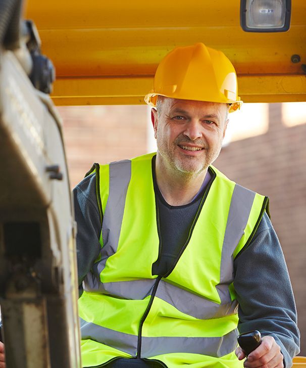 a man wearing a hard hat and safety vest is sitting in a vehicle .