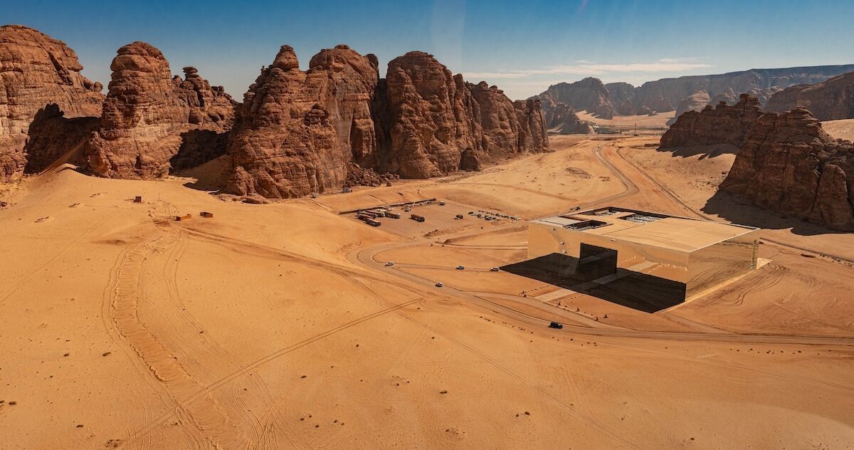 Mosque illuminated at night, dome and minaret aglow, arched entrance, warm colors, stone structure.
