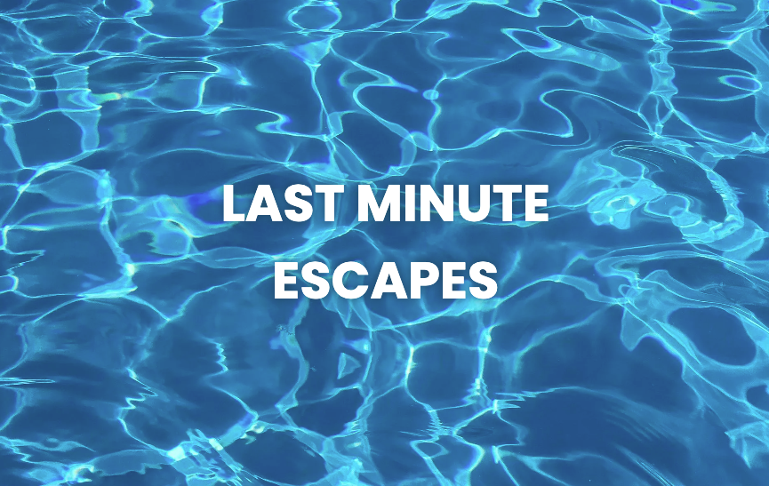 Beach with turquoise water, swimmers, and people on the sandy shore on a sunny day.