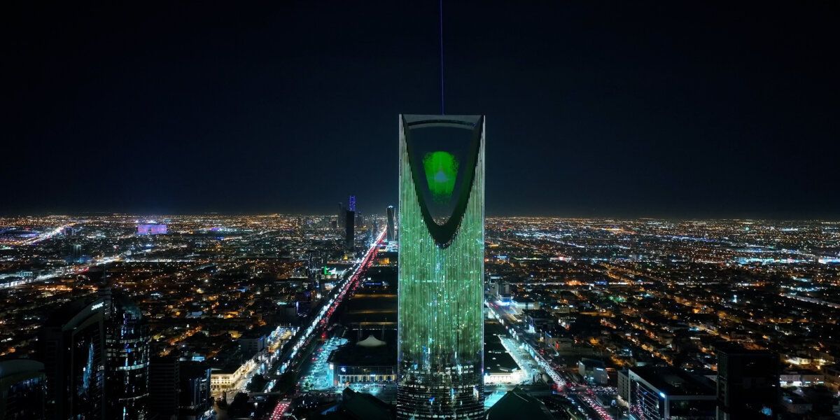 Wooden boat in turquoise water, harbor with white yachts and buildings in background.