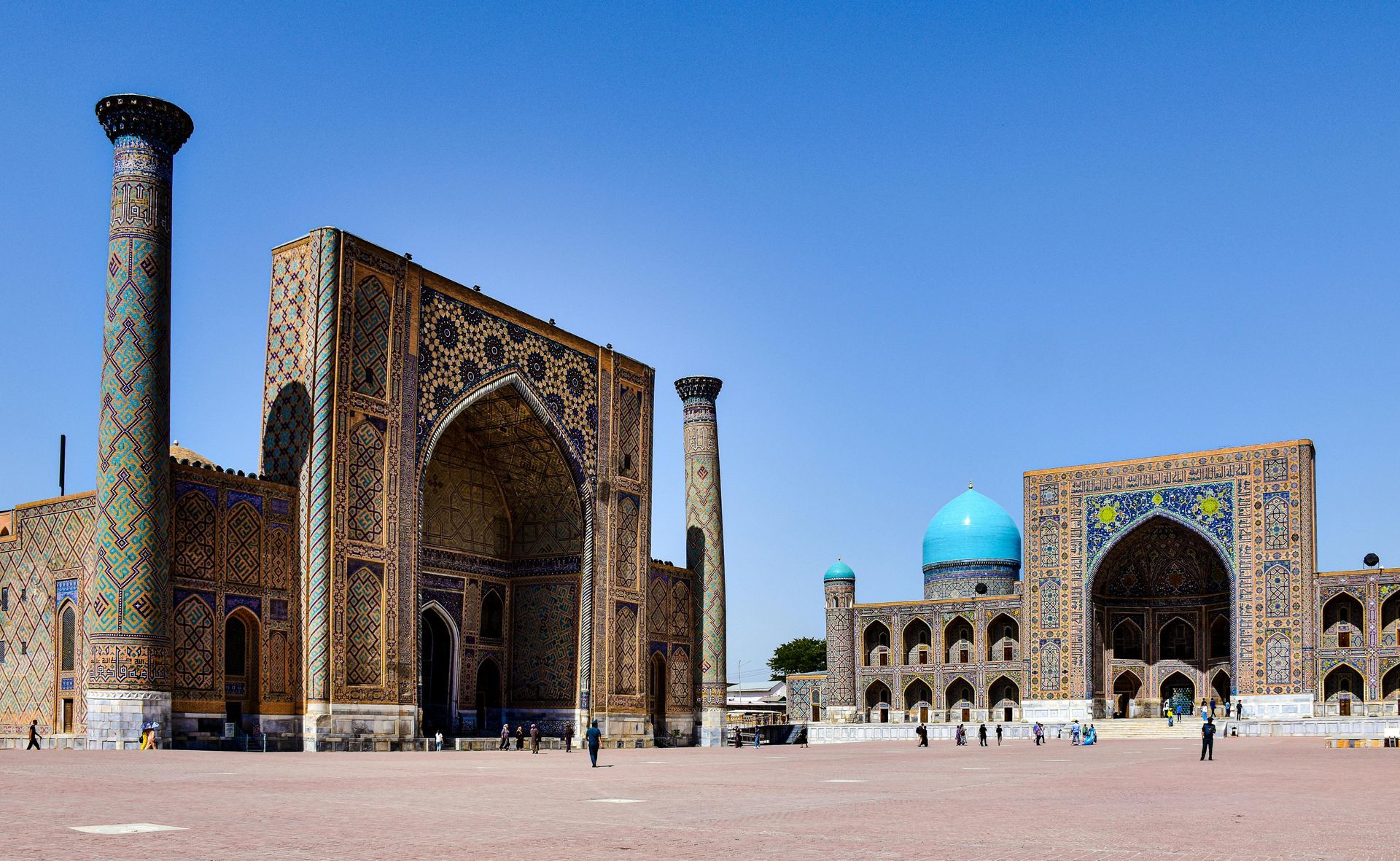 Mosque illuminated at night, dome and minaret aglow, arched entrance, warm colors, stone structure.