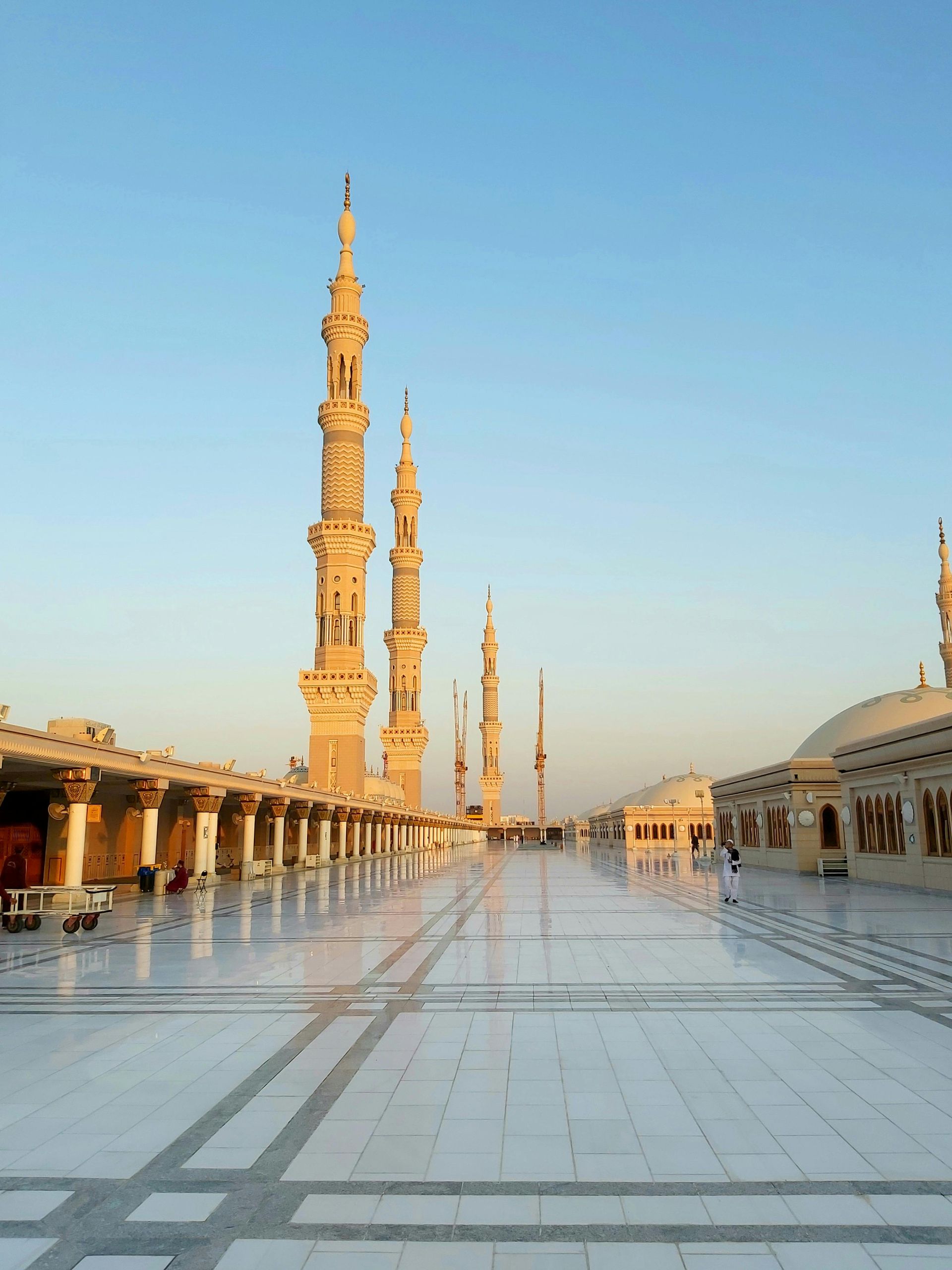 Exterior view of Al-Masjid an-Nabawi in Medina with tall minarets under a clear sky.