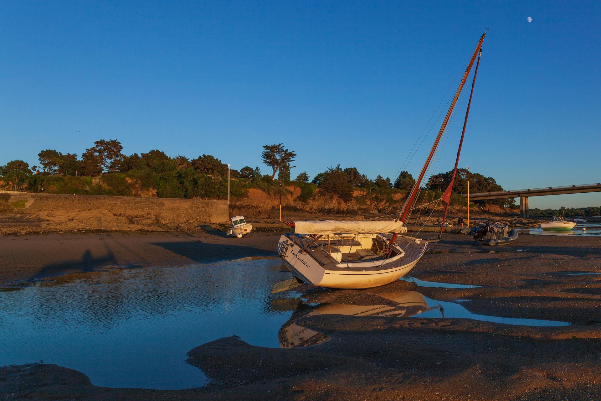 Wooden boat in turquoise water, harbor with white yachts and buildings in background.