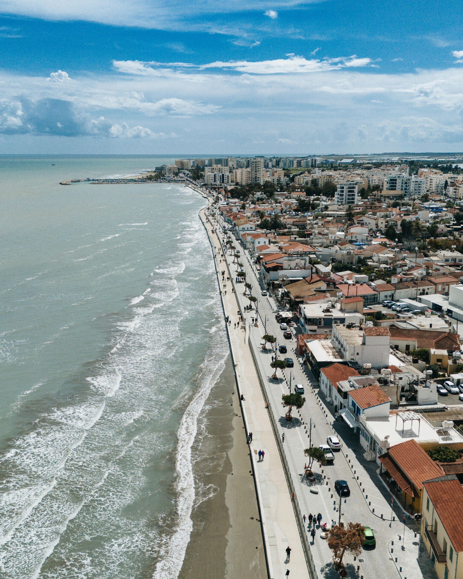 Wooden boat in turquoise water, harbor with white yachts and buildings in background.