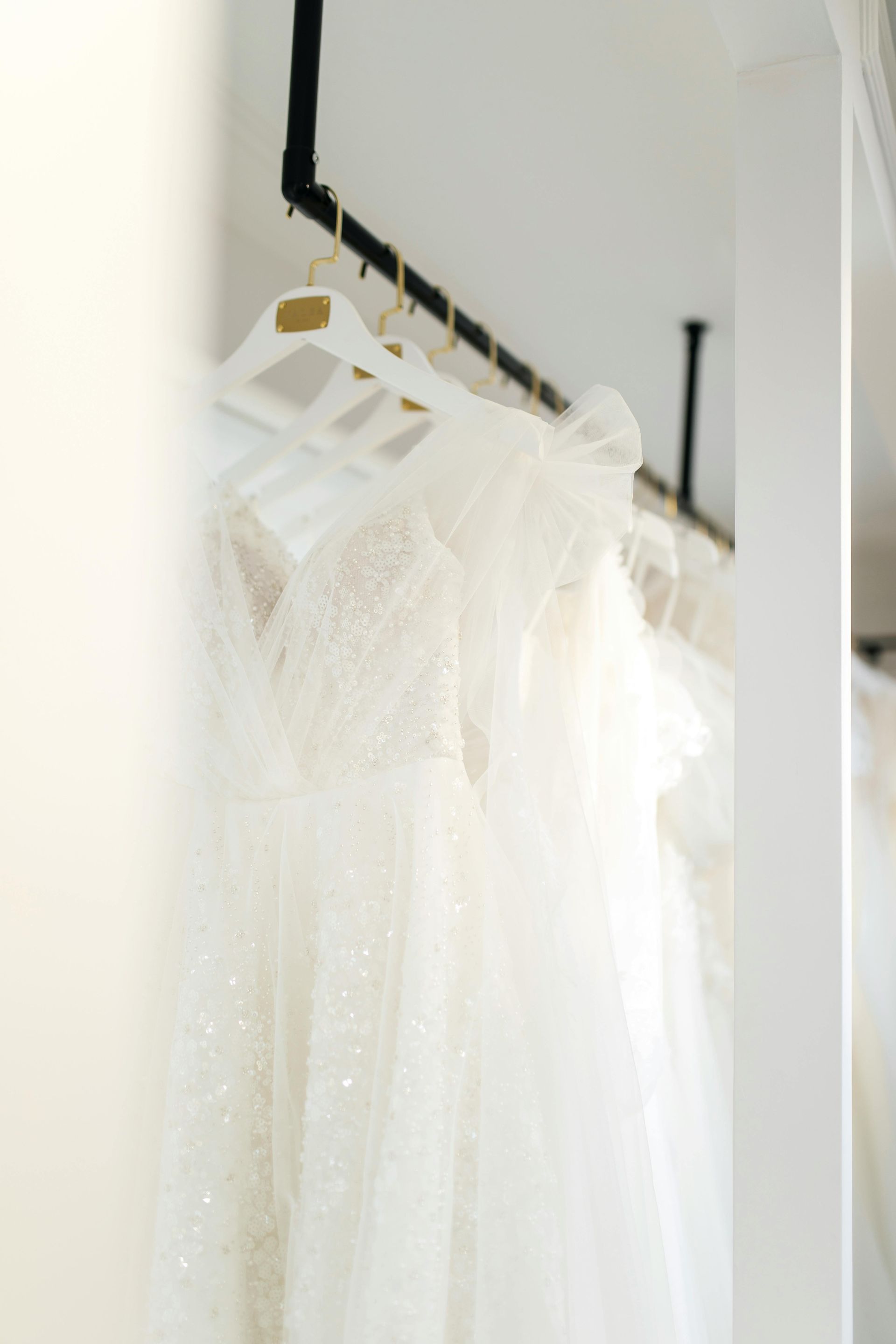 White wedding dresses hanging on a rack in a boutique.