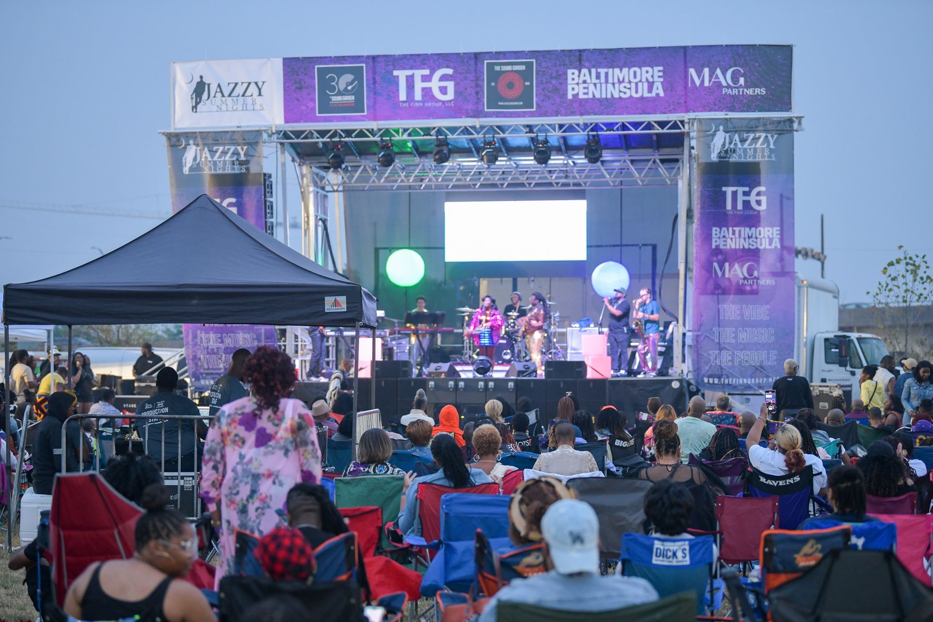 A crowd of people are sitting in chairs in front of a stage at a concert.