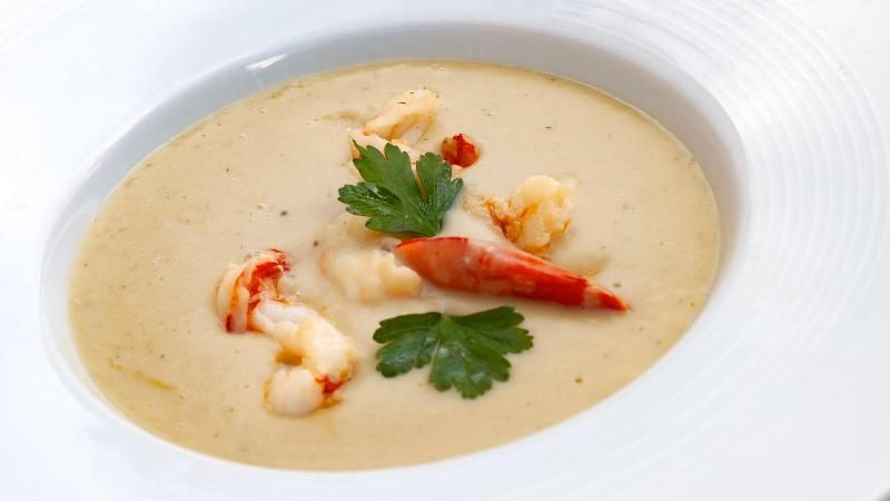 Una ciotola di zuppa con gamberi e prezzemolo sopra.