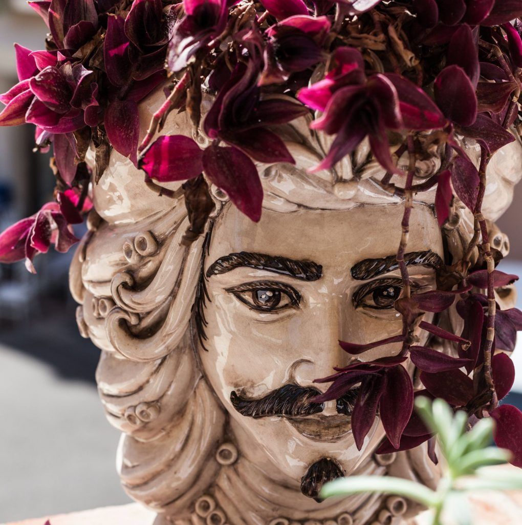 Una statua di un uomo con fiori viola sulla testa