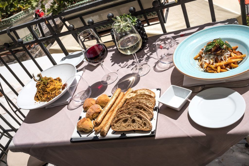 Un tavolo sormontato da piatti di cibo e bicchieri di vino.