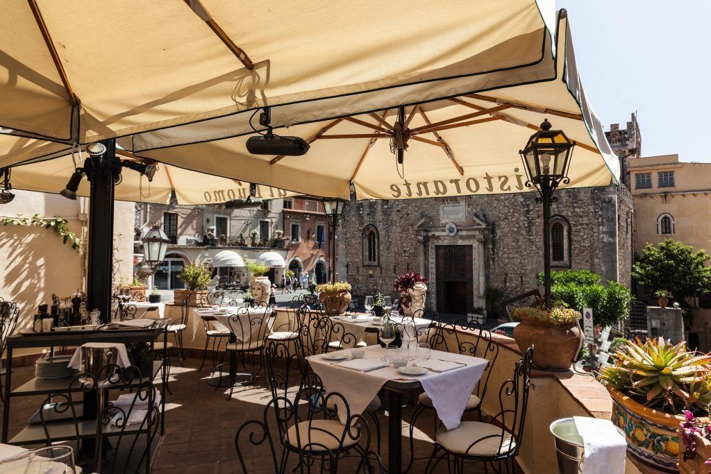 Un ristorante con tavoli e sedie sotto gli ombrelloni